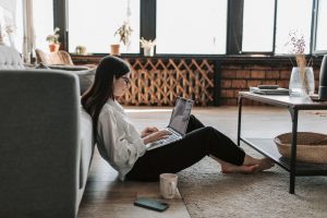 A woman sitting on the floor with a laptop in her lap