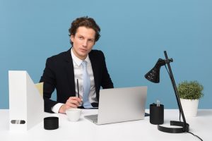 A man in a suit in front of a laptop.