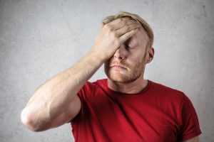 A worried man putting the palm of his hand to his forehead