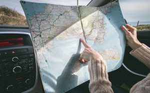 A woman planning a move to Arizona while pointing at a map and sitting in the car