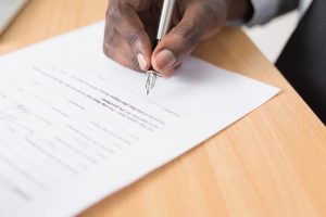 A person signing an agreement about selling a house