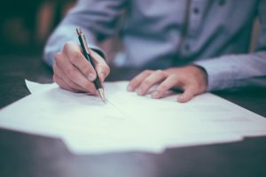 a man signing a lot of documents when selling your house in a hurry