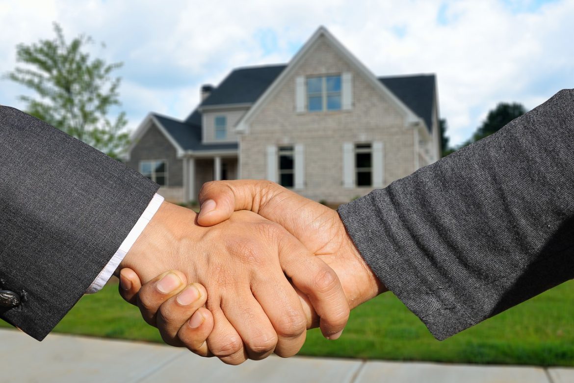 A handshake between two people with a view of a house in the background