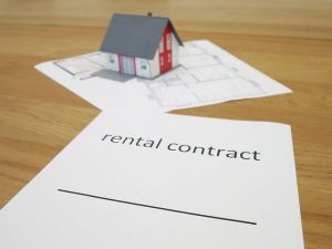 A toy house on a blueprint, and a paper saying “Rental contract”.