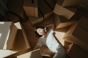 A woman surrounded by cardboard boxes, thinking how spring is the best season to sell your home.