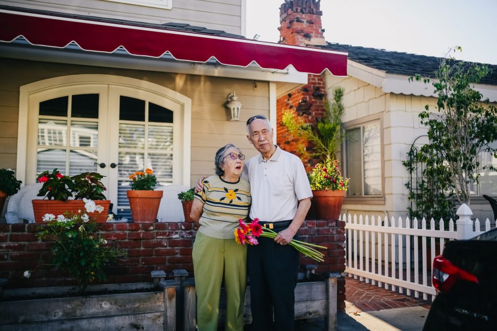 An older couple standing in front of a house