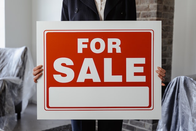 A person holding for sale sign.
