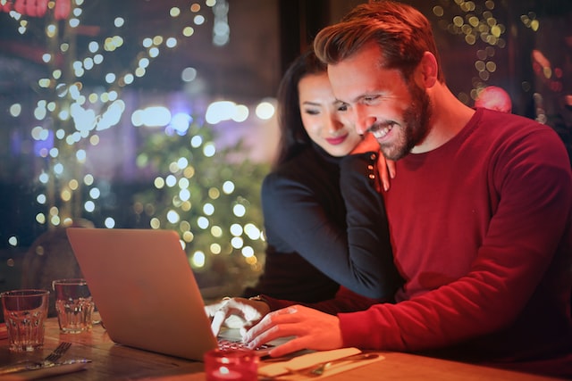 Happy couple reading an unmarried couple's guide to buying a home on a laptop